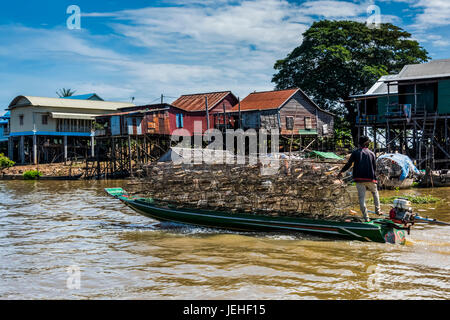 Un homme transportant des marchandises dans un bateau sur une rivière par un village flottant appelé Kampong Phluk ; la province de Siem Reap, Cambodge Banque D'Images