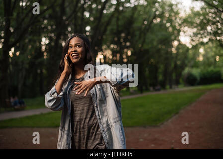 Cheerful afroamerican girl talking on the phone émotionnellement. Banque D'Images