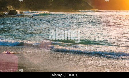 Les enfants surfent sur les vagues dans le coucher du soleil la lumière, Belle Baie Cristal, Nusa Penida Bali Banque D'Images