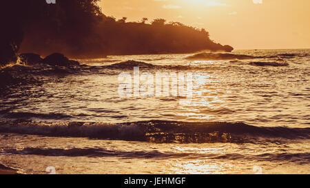 Les enfants surfent sur les vagues dans le coucher du soleil la lumière, Belle Baie Cristal, Nusa Penida Bali Banque D'Images