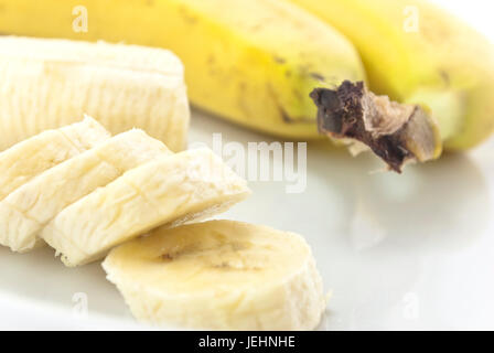 Close-up de tranches de banane sur une plaque blanche avec la Chine, la partie restante et deux ensemble, non pelées bananes au flou en arrière-plan. Banque D'Images