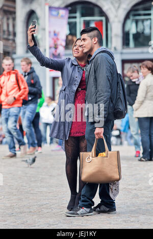 AMSTERDAM-26 AOÛT 2014. Un couple bien habillé prend le selfie sur la place du Dam. La ville est une source d'inspiration pour les gens à la mode. Banque D'Images