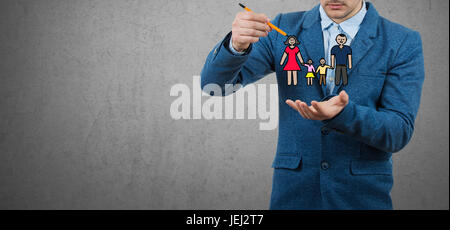 Assurance vie familiale, la protection de la famille, de concepts relatifs à la famille.Businessman holding un crayon dans sa main essayer de tirer une famille heureuse. Banque D'Images