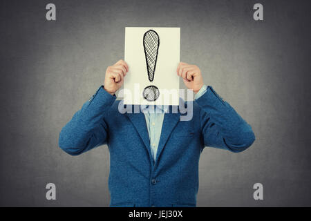Businessman couvrant son visage à l'aide d'un papier d'un point d'exclamation Banque D'Images