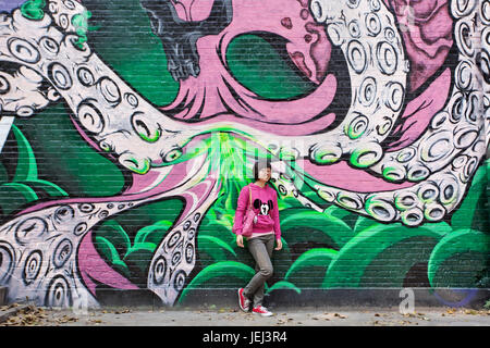 PÉKIN – OCTOBRE. 16, 2010. Une fille pose devant le graffiti dans le quartier artistique de Beijing Dashanzi qui abrite une communauté artistique. Banque D'Images