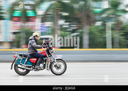 GUANGZHOU-FÉVRIER. 26, 2012. Homme sur une moto Honda sur la route avec des palmiers en mouvement flou sur l'arrière-plan. Banque D'Images