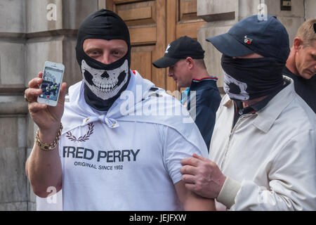 Juin 24, 2017 - Londres, Royaume-Uni - LONDRES, Royaume-Uni. 24 septembre 2017. Un manifestant EDL masqué contient jusqu'son téléphone pour photographier moi comme je prends sa photo à l'extérieur du pub Wetherspoons sur Whitehall. La police plus tard accompagné un groupe d'environ 40 à Charing Cross et le bas du talus de backstreet où ils ont été d'organiser un rassemblement. La police avait déjà déplacé plusieurs centaines d'anti-fascistes contre-manifestants organisés par l'UAF à partir de leur parcours jusqu'à une zone séparée du remblai à proximité où ils ont continué à protester bruyamment contre l'EDL jusqu'à ce que la police les a escortés jusqu'à Charing Cross s