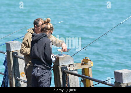 Un couple de personnes à partir d'un quai de pêche sur une journée chaude en été au Royaume-Uni. Banque D'Images