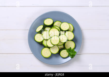 Assiette de tranches de courgette verte sur fond de bois blanc Banque D'Images