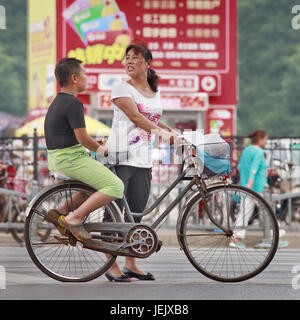 PÉKIN-27 JUILLET 2015. Mère avec son fils de graisse sur la porte-bagages. Le taux d’obésité chinois a grimpé en flèche au cours des dernières décennies. Banque D'Images