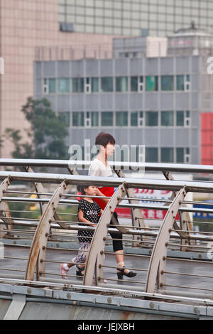 PÉKIN-27 JUILLET 2015. Femme aînée avec petite-fille sur pont piéton. Les Chinois plus âgés jouent souvent un rôle actif dans la levée de leurs petits-enfants. Banque D'Images
