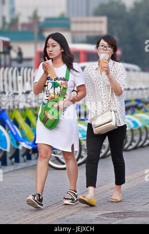 PÉKIN-AOÛT. 5, 2015. Deux filles aiment boire un verre doux pendant la marche. Bureau national de la statistique Chine 1 femme sur 5 entre 25 et 29 ans reste non mariée. Banque D'Images