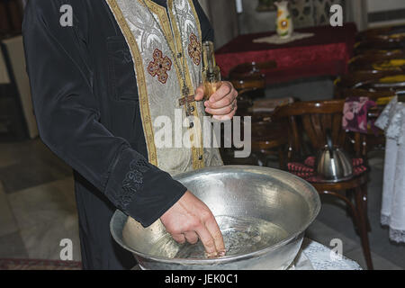 L'assistant prêtre Baptême font baptismal rempli d'eau bénite à l'église pendant la cérémonie à Burgas Banque D'Images