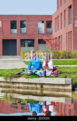 Couple Profitez d'une journée ensoleillée d'automne côté canal avec architecture moderne sur l'arrière-plan. Banque D'Images