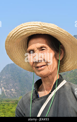 YANGSHUO-CHINE-SEPT. 18, 2006. Femmes âgées local caractéristique avec un chapeau de paille contre un ciel bleu. Banque D'Images