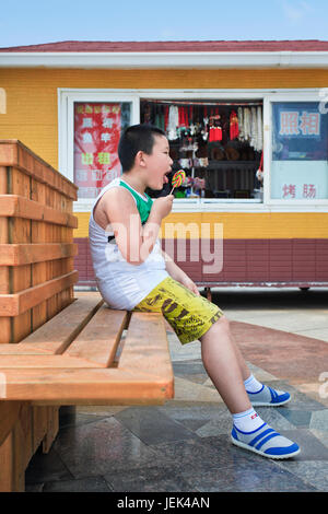 YANTAI-CHINE-JUILLET 17. 13 ans de l'embonpoint Xia Long lèche une sucette. L'obésité chez les enfants et les jeunes est un problème en Chine. Banque D'Images