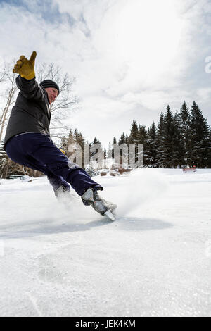 À l'arrêt de vol de sexe masculin sur patins avec ice spray ; Calgary, Alberta, Canada Banque D'Images