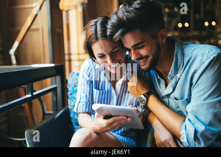 Young attractive cheerful couple sur date dans un café à la tablette à Banque D'Images