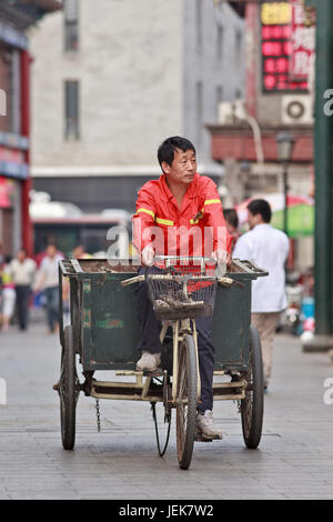 PÉKIN-9 JUIN 2015. Balai de rue sur un vieux tricycle. La Chine a une gigantesque armée de femmes de ménage de rue habillée d'orange pour nettoyer les rues dans des denses . Banque D'Images