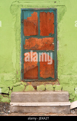 Porte en métal rouillé avec peel off peinture à un mur vert Banque D'Images