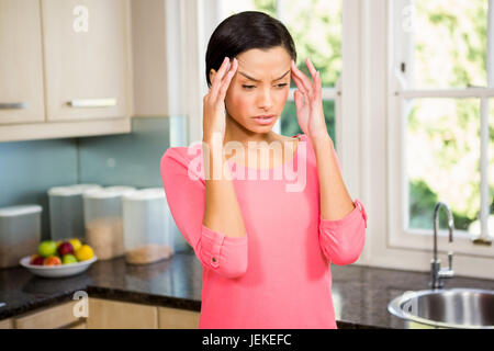 Fronçant brunette avec les mains sur le visage Banque D'Images