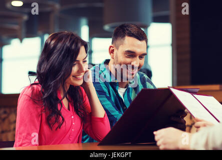 Smiling couple avec des menus au restaurant Banque D'Images