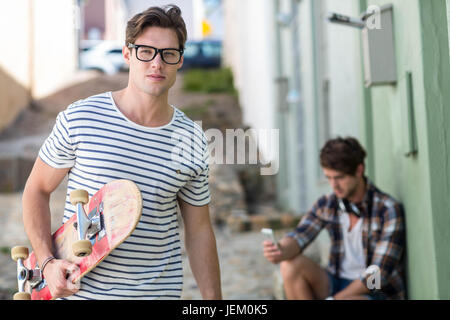 Hip man holding skateboard Banque D'Images