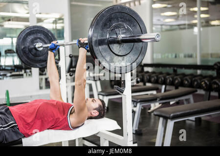 L'homme musclé sur un banc d'haltères de levage Banque D'Images