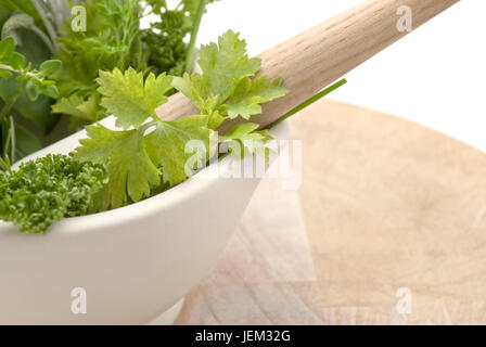 Libre d'une sélection d'herbes dans un mortier à main de couleur crème sur la planche à découper en bois usé. L'objet se coupe au bord gauche du châssis. Isolat Banque D'Images