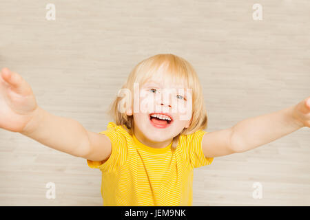 Cute boy stretching hands up and looking at camera Banque D'Images