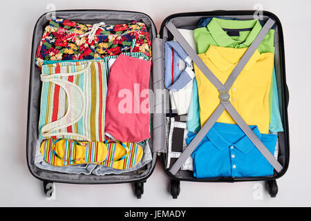 Des vêtements colorés dans des valises ouvertes. L'homme et de la femme accessoires d'été. Le temps d'aller sur la plage. Banque D'Images