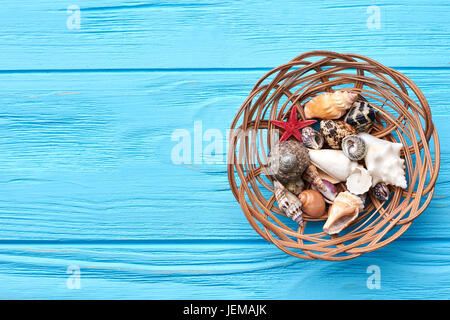 Les coquillages dans le panier, fond bleu. De coquillages. Banque D'Images