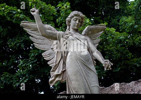 Statue d'un ange tenant une fleur et pointant vers les cieux dans le cimetière Grange, Édimbourg. Banque D'Images