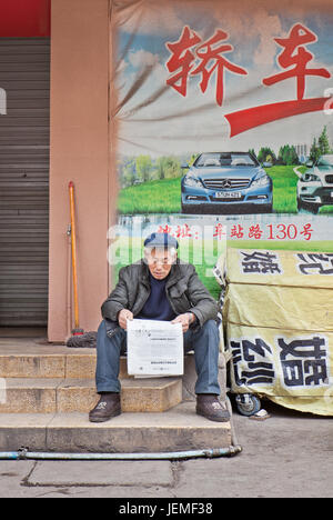 Chinese man reading newspaper. Les caractères chinois comptent par dizaines de milliers. La lecture des journaux nécessite la connaissance d'environ 3000 caractères. Banque D'Images