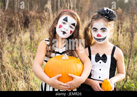 Les filles avec des visages peints holding pumpkins Banque D'Images