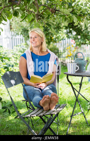 Woman Reading book in garden Banque D'Images