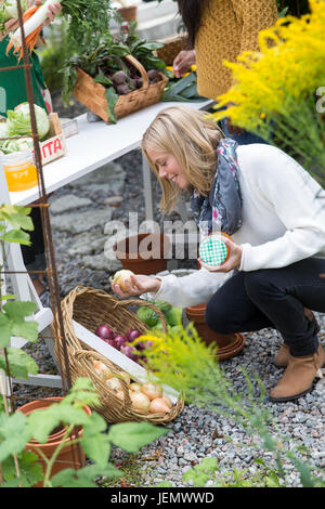 Jeune femme à la recherche de légumes cultivés à la maison Banque D'Images