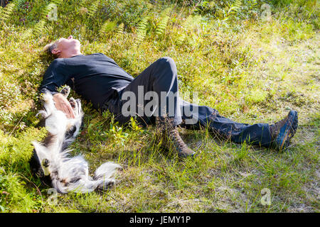 L'homme et le chien couché sur l'herbe ensemble Banque D'Images