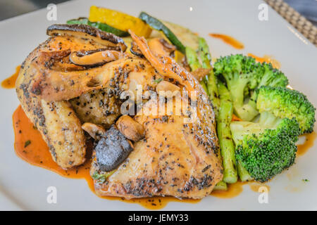 Poulet rôti au four à bois au citron et au romarin servi avec légumes méditerranéens grillés Banque D'Images