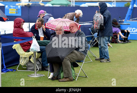 Sussex Eastbourne, Royaume-Uni. 27 Juin, 2017. Les spectateurs à l'abri sous les parasols en pluie arrête de jouer à l'International Aegon tennis Eastbourne tournoi comme un mélange de pluies et d'orages dans le sud-est de la Grande-Bretagne aujourd'hui Crédit : Simon Dack/Alamy Live News Banque D'Images