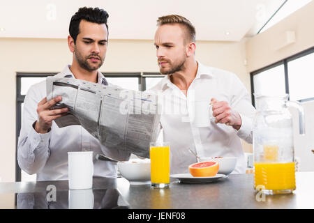 Couple gay concentré reading newspaper Banque D'Images