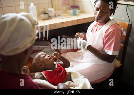 L'infirmière administre un médicament à un enfant par voie intraveineuse à un hôpital de Bundibugyo, Ouganda. Banque D'Images