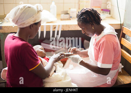 L'infirmière administre un médicament à un enfant par voie intraveineuse à un hôpital de Bundibugyo, Ouganda. Banque D'Images