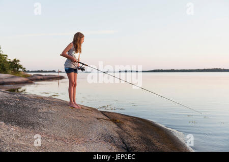 Girl pêche en mer, au crépuscule Banque D'Images