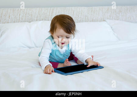 Smiling baby jouer avec une tablette Banque D'Images