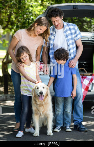 Smiling family standing in front of a car Banque D'Images