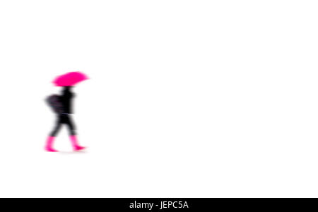 Une femme avec des bottes rose une un parapluie rose marche dans la neige Banque D'Images