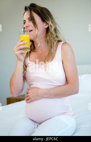 Fatigué pregnant woman drinking orange juice Banque D'Images