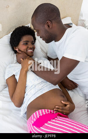 Pregnant couple cuddling on bed Banque D'Images
