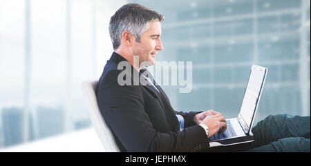 Image composite de businessman using laptop Banque D'Images